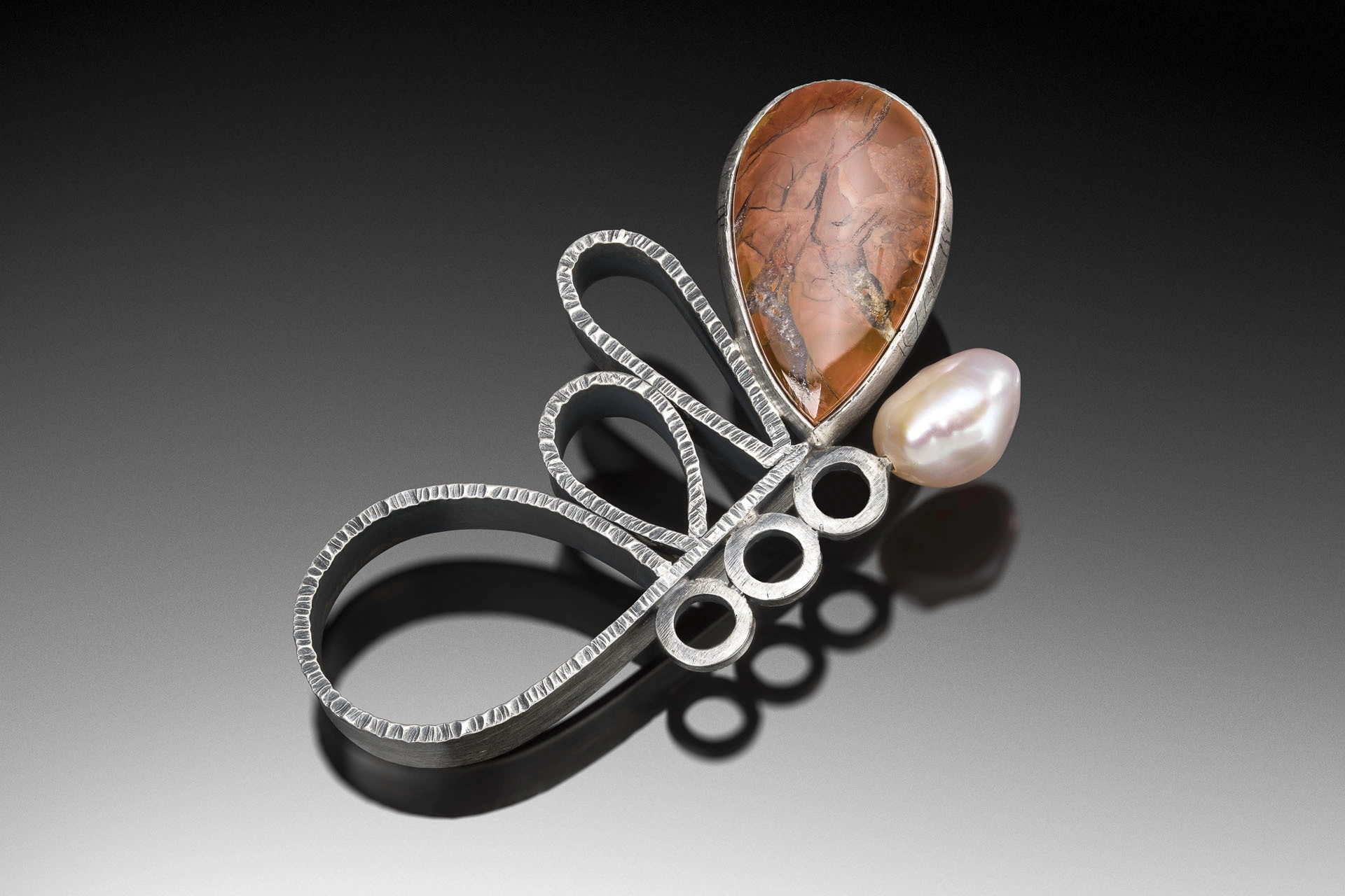 Actual open-loop portfolio work with warm-toned insert and pearl-like element, preserving the original ground and reflection